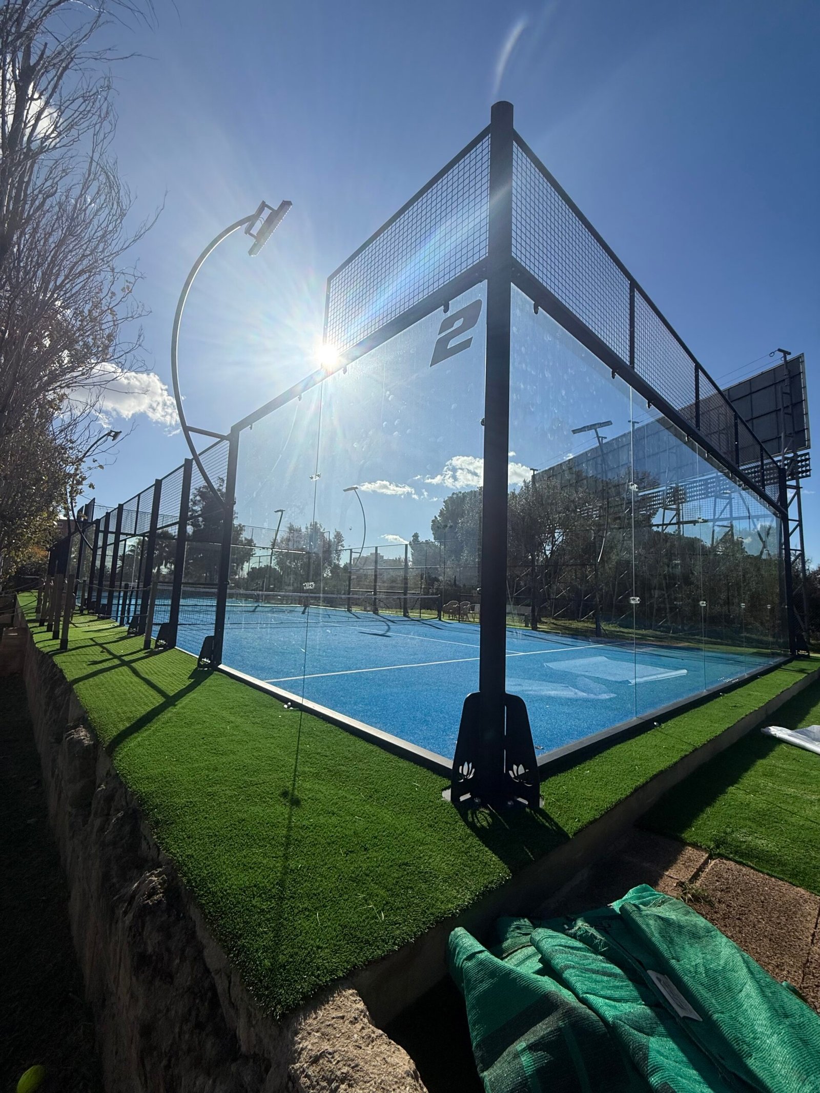 Pista de pádel con suelo azul instalada junto a pista de tierra