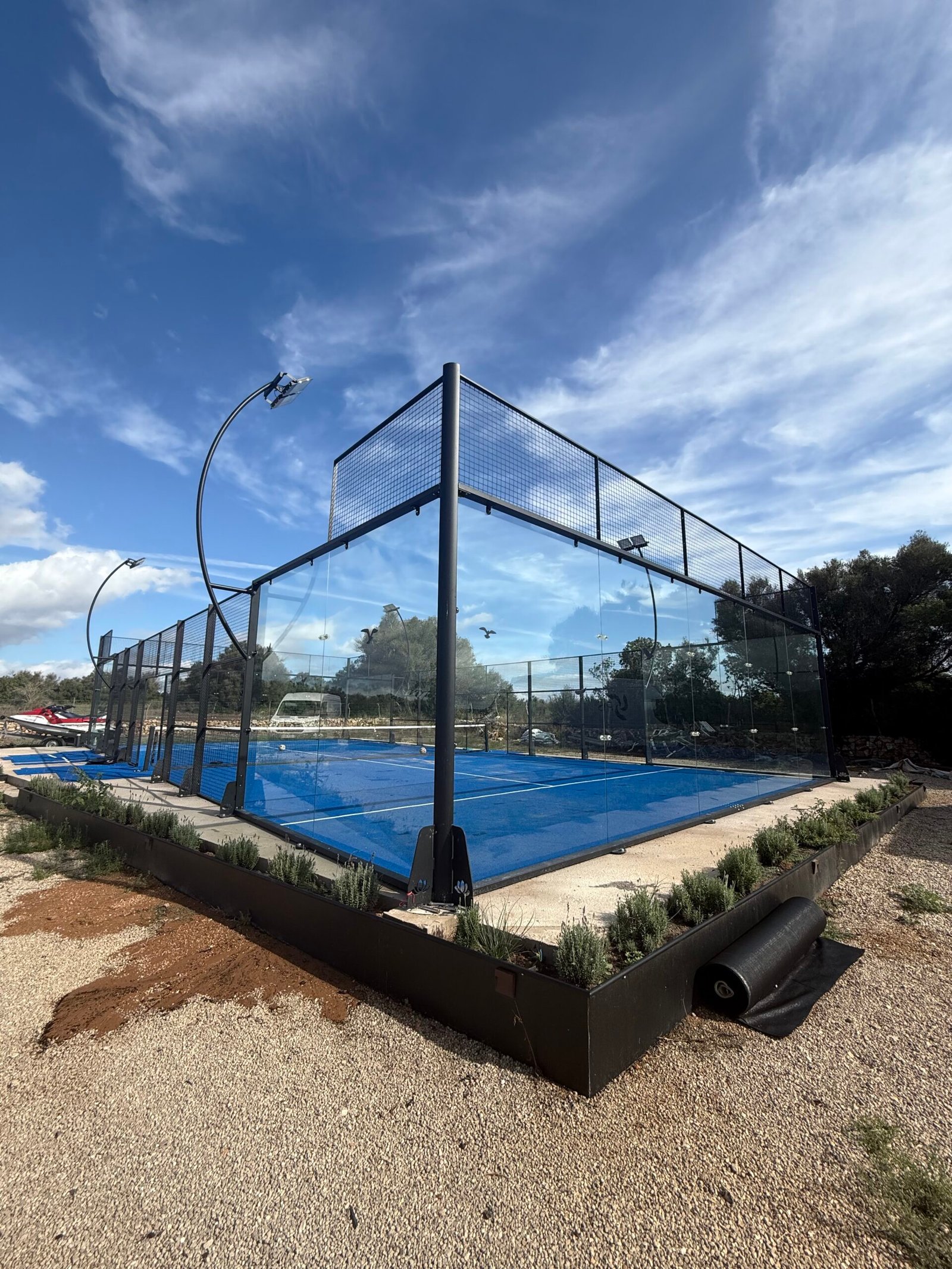 Pista de pádel con suelo azul junto a palmeras