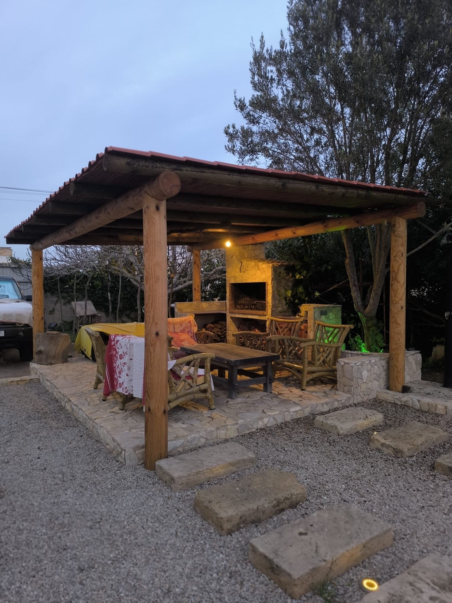 Pérgola con techo de tejas rojas y barbacoa iluminada al atardecer