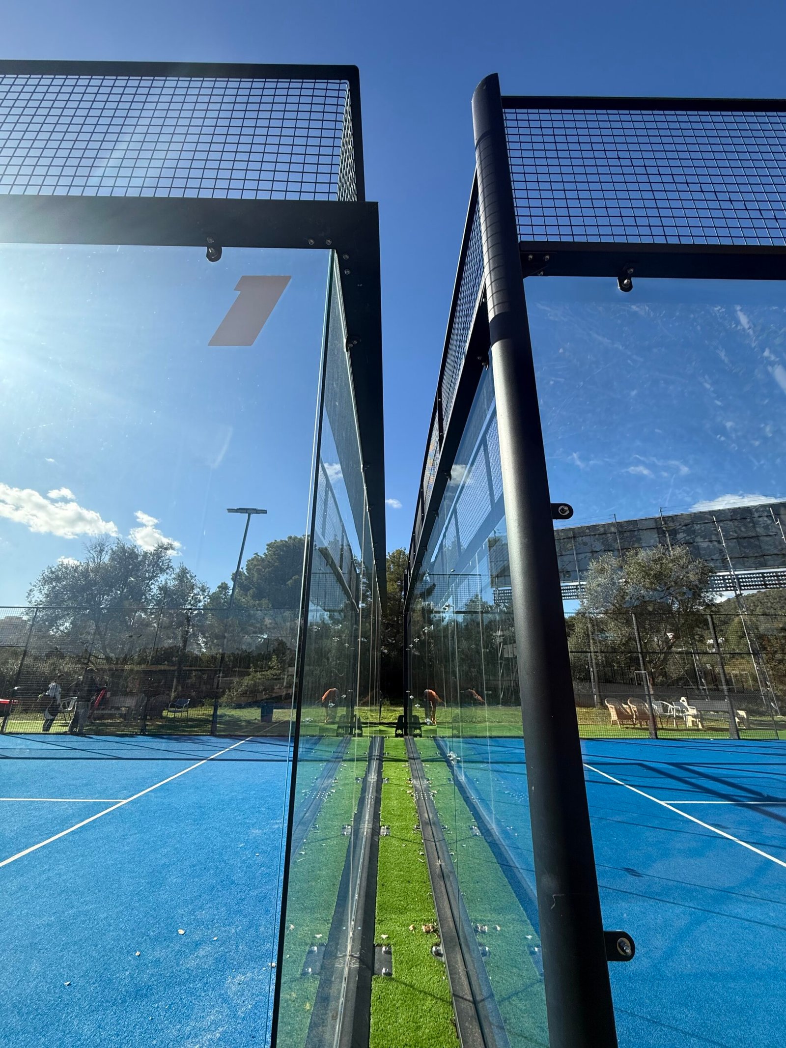Detalle de cristal templado de pista de pádel con reflejo de sol