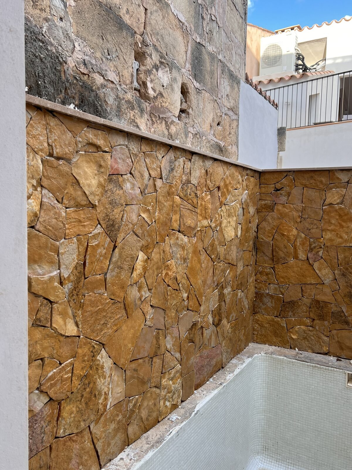 Esquina de muro junto a piscina revestido con piedra natural