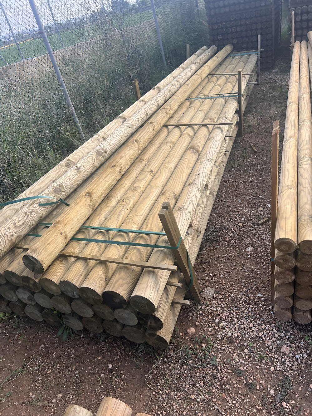 Filas de postes de madera tratados en el patio