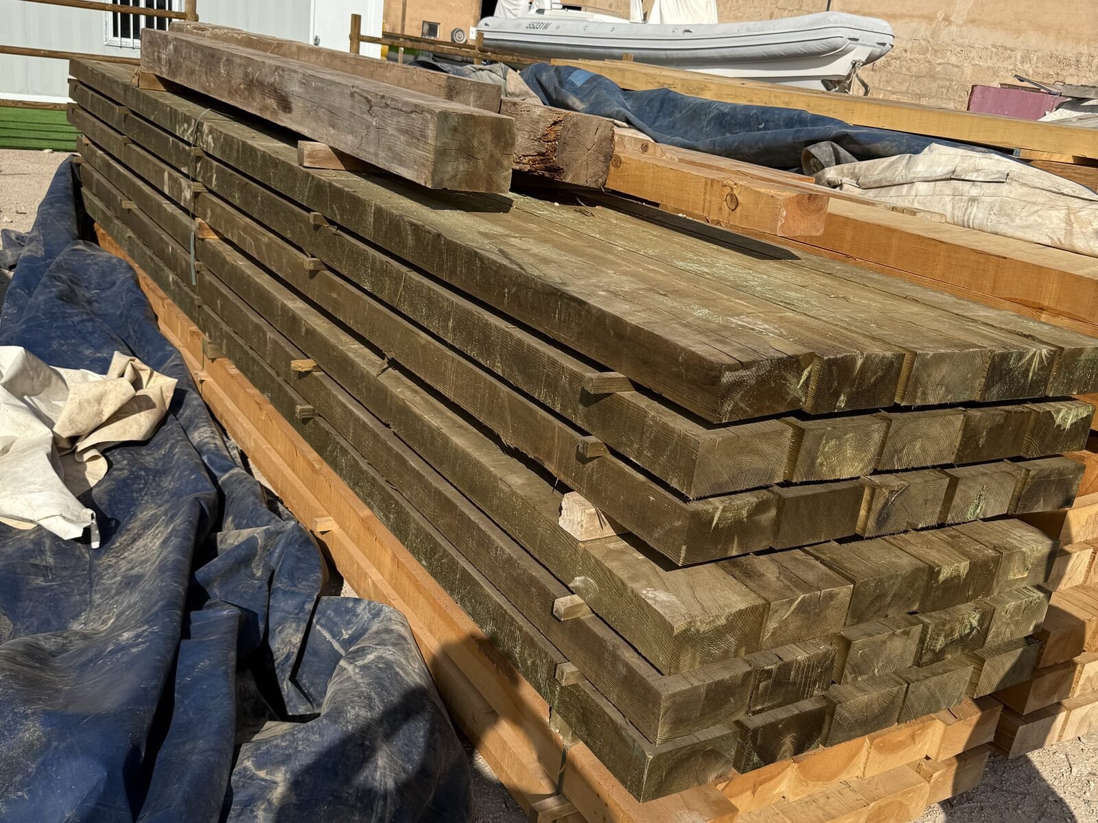 Vigas de madera tratada apiladas junto a nave industrial