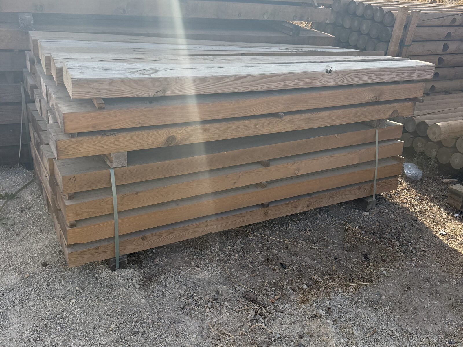 Vigas de madera apiladas con destello de sol