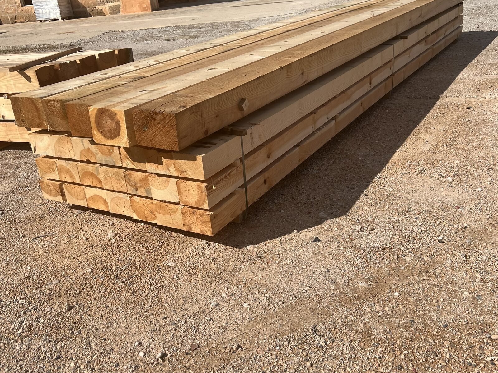 Vigas de madera apiladas junto a la fachada del almacén